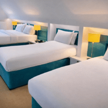 Bright triple room with three cosy beds, modern lighting, and a scenic window view for a relaxing stay.