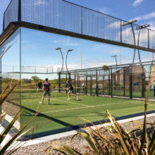 Guests enjoying a lively game on the hotel's modern outdoor padel court under clear blue skies.