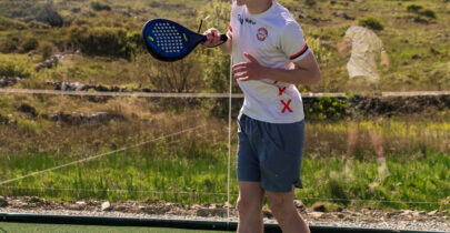 Guest playing tennis on scenic outdoor court with hills in background, enjoying active facilities at luxury hotel.