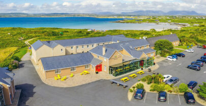 Coastal hotel with ocean views, spacious parking, lush greenery, and vibrant outdoor seating near scenic coastline.